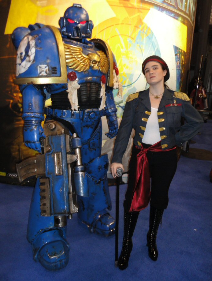 Photo of Christina dressed as Rogue Trader Astra Kezzek standing next to an Ultramarine